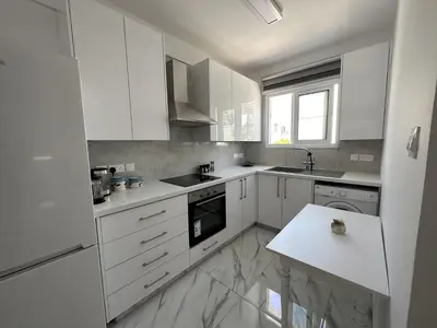a white kitchen with white cabinets and a counter at Modern Seaside Retreat Near Nissi Beach in Ayia Napa