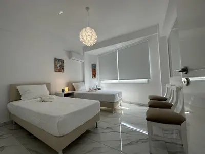 a white bedroom with two beds and a window at Modern Seaside Retreat Near Nissi Beach in Ayia Napa