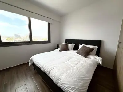 a bedroom with a white bed with a large window at Rachel 401 in Larnaka