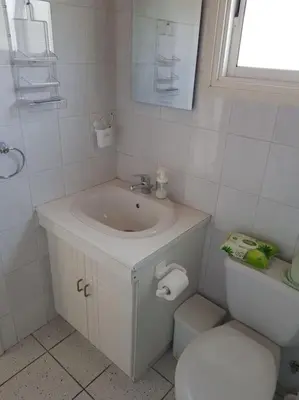 a white bathroom with a sink and a toilet at On the beachfront, AYIA THEKLA, AGIA NAPA MARINA in Ayia Napa