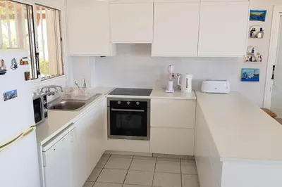 a white kitchen with white cabinets and a sink at On the beachfront, AYIA THEKLA, AGIA NAPA MARINA in Ayia Napa