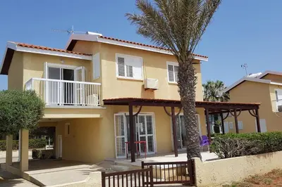 a house with a palm tree in front of it at On the beachfront, AYIA THEKLA, AGIA NAPA MARINA in Ayia Napa