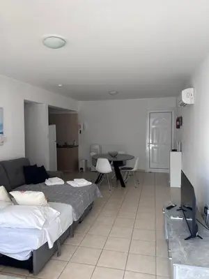 a living room with two beds and a television at Beautiful 2 Bed Ground Floor Apartment With Pool in Paralimni