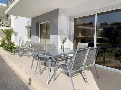 a glass table and chairs on a patio at Beautiful 2 Bed Ground Floor Apartment With Pool in Paralimni