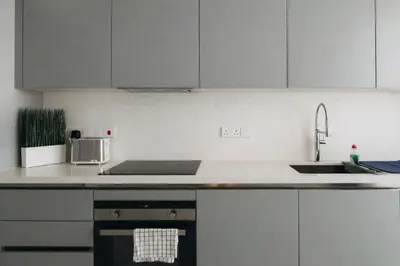 a kitchen with white cabinets and a sink and a stove at New Luxury 2BR Seaview Apt, Sun City, Pool and Beach in Ayia Napa