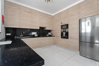 a kitchen with wooden cabinets and a stainless steel refrigerator at Levanda Hills Escape in Protaras in Paralimni