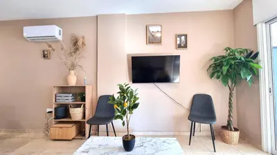 a living room with two chairs and a tv on the wall at 2 Beachside Apts, 5min Walk to Shore with Internet in Larnaka
