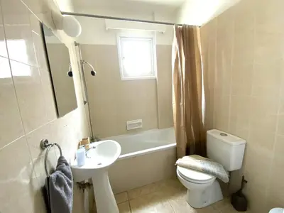 a bathroom with a sink and a toilet and a bath tub at 2 Beachside Apts, 5min Walk to Shore with Internet in Larnaka