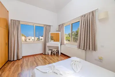 a bedroom with a bed and two large windows at Anthorina Greco Villa #10 in Protaras