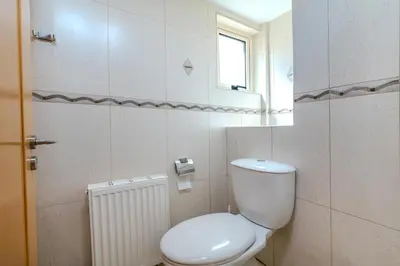 a white bathroom with a toilet and a window at Anthorina Greco Villa #10 in Protaras