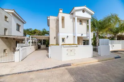 a white house with white fences and palm trees at Anthorina Greco Villa #10 in Protaras