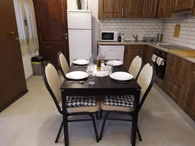 a kitchen with a black table and chairs with wine glasses at Monolithos Cottage in Pachna