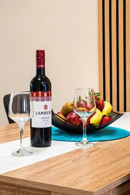 a bottle of wine and two glasses on a table at Sunday's Apartment in Paralimni