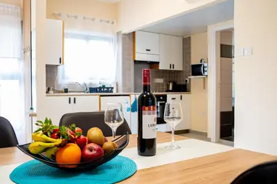 a table with a bowl of fruit and a bottle of wine at Sunday's Apartment in Paralimni