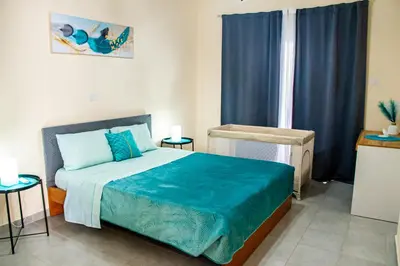 a bedroom with a bed with blue sheets and a window at Sunday's Apartment in Paralimni