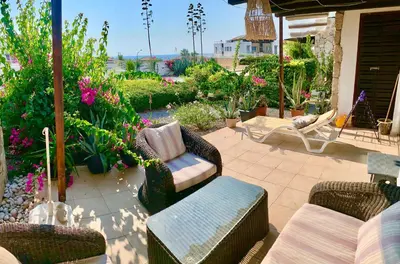 a patio with two chairs and a couch and flowers at Boho Beach Apartment in Tatlisu