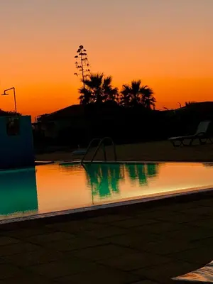 an empty swimming pool with a sunset in the background at Boho Beach Apartment in Tatlisu