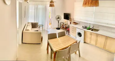 a kitchen and living room with a table and chairs at Boho Beach Apartment in Tatlisu