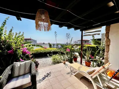 a patio with a bench and potted plants at Boho Beach Apartment in Tatlisu
