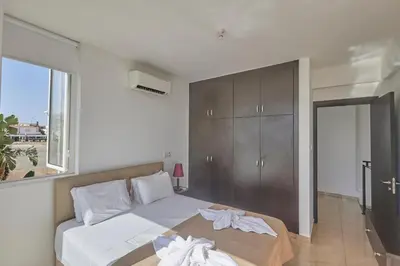 a bedroom with a bed with white sheets and a window at Pearl Villas in Protaras