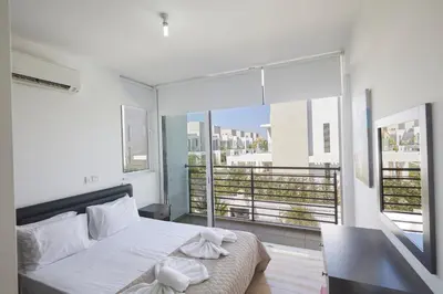a bedroom with a white bed and a large window at Pearl Villas in Protaras