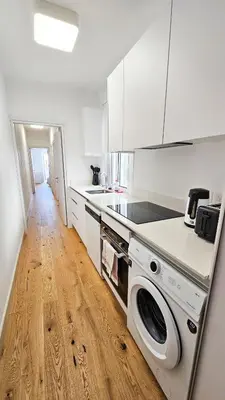a kitchen with white cabinets and a washer and dryer at Larnaca Beach Bliss Apartment in Larnaka