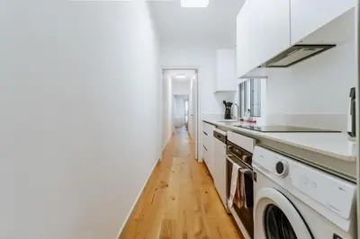 a kitchen with white appliances and a wooden floor at Larnaca Beach Bliss Apartment in Larnaka