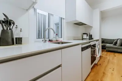 a kitchen with white cabinets and a sink at Larnaca Beach Bliss Apartment in Larnaka