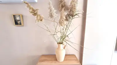 a white vase sitting on a wooden table with flowers at 2 Cozy Apts, Fast Internet, 5 Min Walk to Beach! in Larnaka