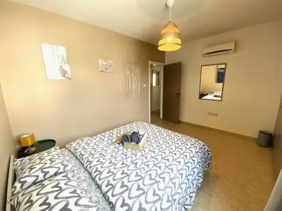 a bedroom with a bed with a white and black comforter at Spacious 3Apt Combo, Fast WiFi, 5Min Walk to Beach in Larnaka