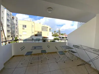 a balcony with chairs and tables on a building at Spacious 3Apt Combo, Fast WiFi, 5Min Walk to Beach in Larnaka