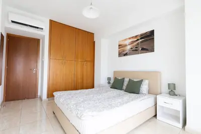 a bedroom with a large bed and a wooden cabinet at Cozy Apartment with Sea View in Larnaka