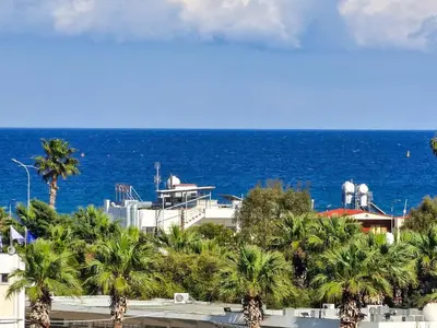 a view of the ocean with palm trees and a building at Charming 3-Bed Duplex with Stunning Sea View in Larnaka