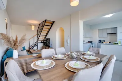 a dining room and kitchen with a wooden table and chairs at Charming 3-Bed Duplex with Stunning Sea View in Larnaka
