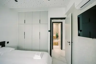 a bedroom with a white bed and a television at 2BR Amalfi Blue Apt in Larnaca - Pool & 10Min Walk to Mackenzie Beach! in Larnaka