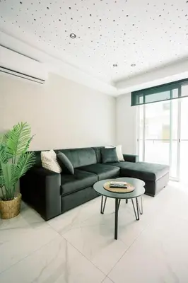 a living room with a green couch and a table at 2BR Amalfi Blue Apt in Larnaca - Pool & 10Min Walk to Mackenzie Beach! in Larnaka
