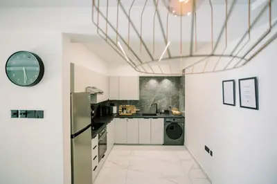 a kitchen with white cabinets and a washer and dryer at 2BR Amalfi Blue Apt in Larnaca - Pool & 10Min Walk to Mackenzie Beach! in Larnaka