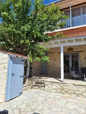 a house with a white door on a stone patio at Vouno Vouni Cottage in Vouni