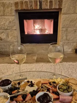 two glasses of white wine next to a plate of food at Vouno Vouni Cottage in Vouni