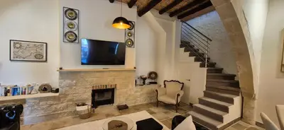 a living room with a staircase with a tv and a fireplace at Vouno Vouni Cottage in Vouni
