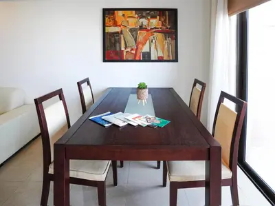 a wooden dining room table with chairs and a painting at Stylish 2BR Apartment with Balcony and Parking near Saint Lazarus and Finikoudes Beach in Larnaka