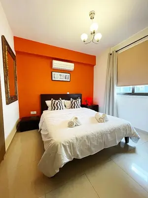 a bedroom with a bed with an orange wall at Stylish 2BR Apartment with Balcony and Parking near Saint Lazarus and Finikoudes Beach in Larnaka