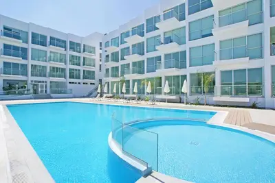 a large swimming pool in front of a building at Too Coool Studio Apartment Coralli Resort in Protaras