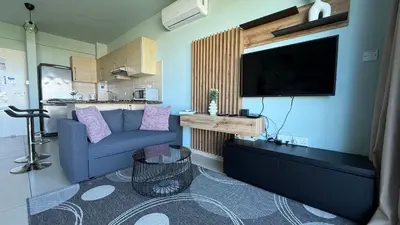 a living room with a blue couch and a flat screen tv at Too Coool Studio Apartment Coralli Resort in Protaras