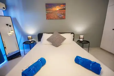 a large white bed with two blue pillows on it at Anteia's Seaview Suite just steps from Finikoudes Beach Larnaca in Larnaka