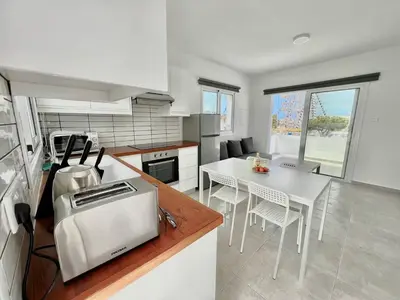 a kitchen with a table and a counter top at Protaras Cozy2bedroom Apartment in Paralimni