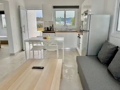 a kitchen and living room with a table and a couch at Protaras Cozy2bedroom Apartment in Paralimni