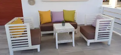 a bench with colorful pillows and a table and chairs at Makenzy Mermaid 2 Bedroom Apartment in Larnaka