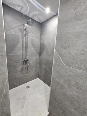 a bathroom with a shower with gray tile at Makenzy Mermaid 2 Bedroom Apartment in Larnaka