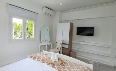 a white bedroom with a bed and a chair at Landina villa in Protaras